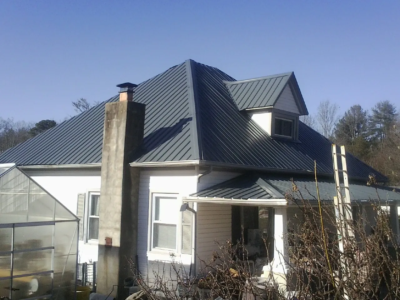 Dark blue standing seam metal roof on a white farmhouse with dormer — Slate & Tile Roof Repair by Roofing Brothers in Medimont