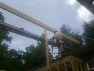 Carpenter setting a ridge beam over a new addition frame — Ice Dam Removal by Roofing Brothers in Medimont