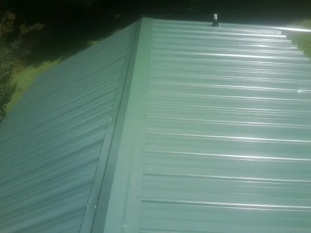 New green metal panels meeting at the ridge of a roof — Flat Roof Repair work by our crew in Medimont