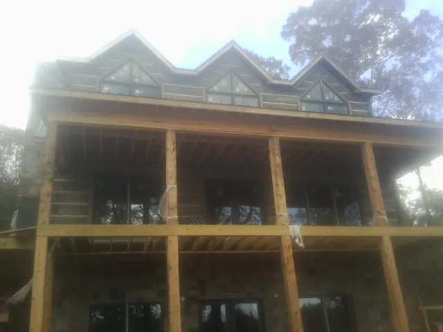 Dormers and porch framing on a large log home under construction — Roof Coating work by our crew in Medimont