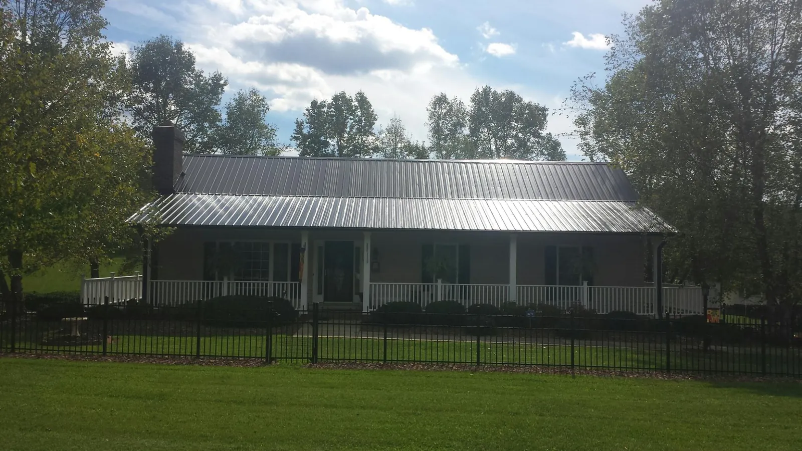 Gray metal roof on a brick ranch with a full width front porch — Gutter Guard Installation work by our crew in Medimont