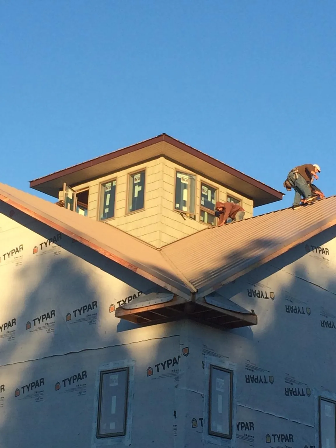 Roofers working around a rooftop cupola on a new metal roof at sunset — Roof Waterproofing in Medimont by Roofing Brothers